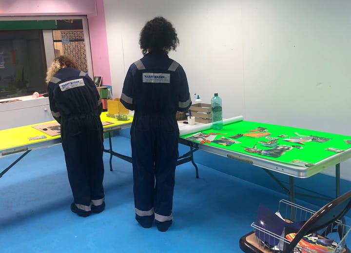 Two people in boiler suits creating zones at tables. 